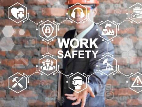 Person wearing a suit and hard hat behind a graphic reading WORK SAFETY