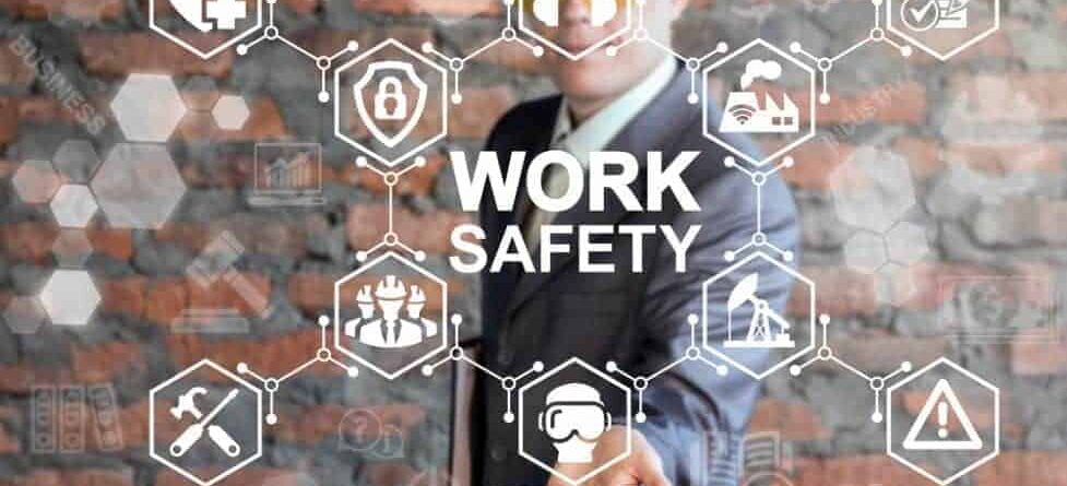 Person wearing a suit and hard hat behind a graphic reading WORK SAFETY