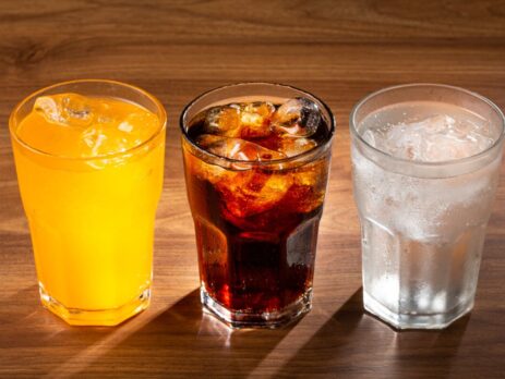 Three glasses of fizzy drinks; orange, cola, and lemonade