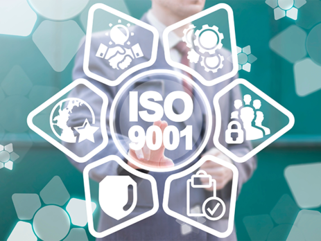 Person wearing a suit standing behind a graphic saying ISO 9001
