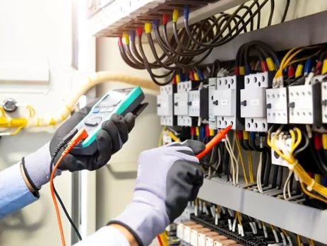 Electrical engineer using a digital multimeter to check electric current voltage in a power distribution board