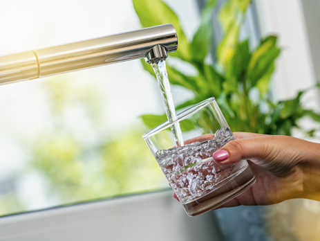 Woman holding a glass under a running tap