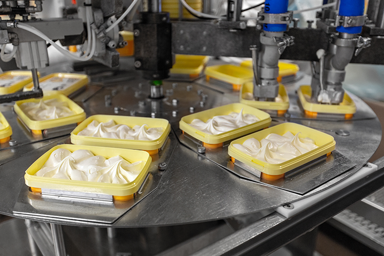Ice cream being packaged into tubs in a factory