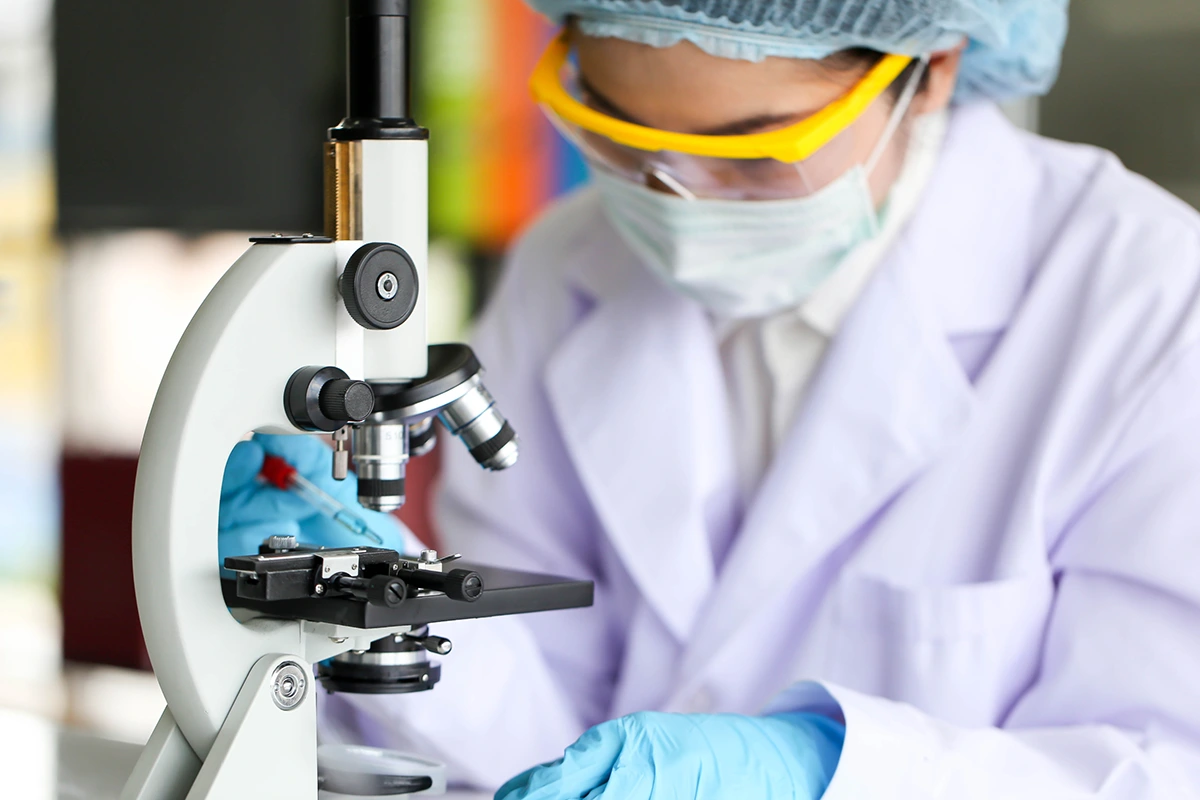 A biochemist studying a sample under a microscope