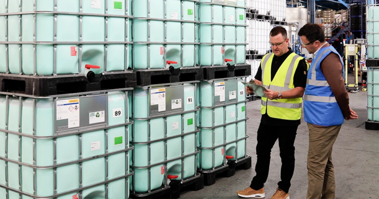 Workers inspecting IBCs of green chemicals