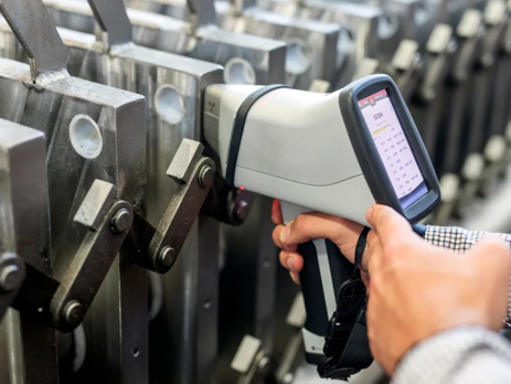A person using an XRF scanner to check the composition of the metal plates.