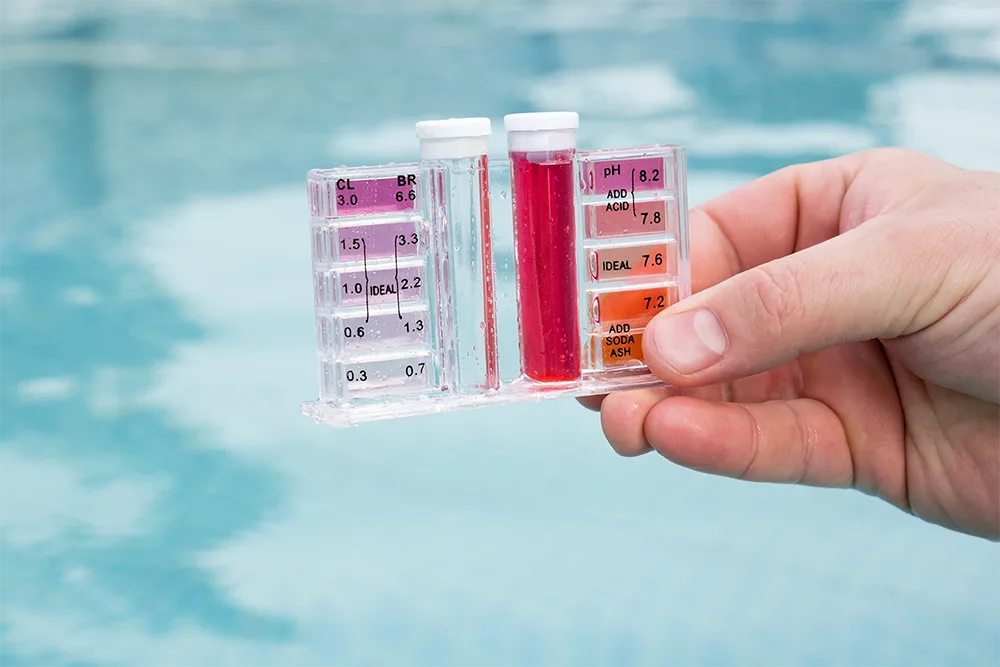 Chlorine analysis kit held infront of swimming pool