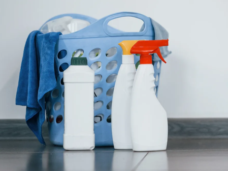Bottles of bleach and sprays next to washing basket