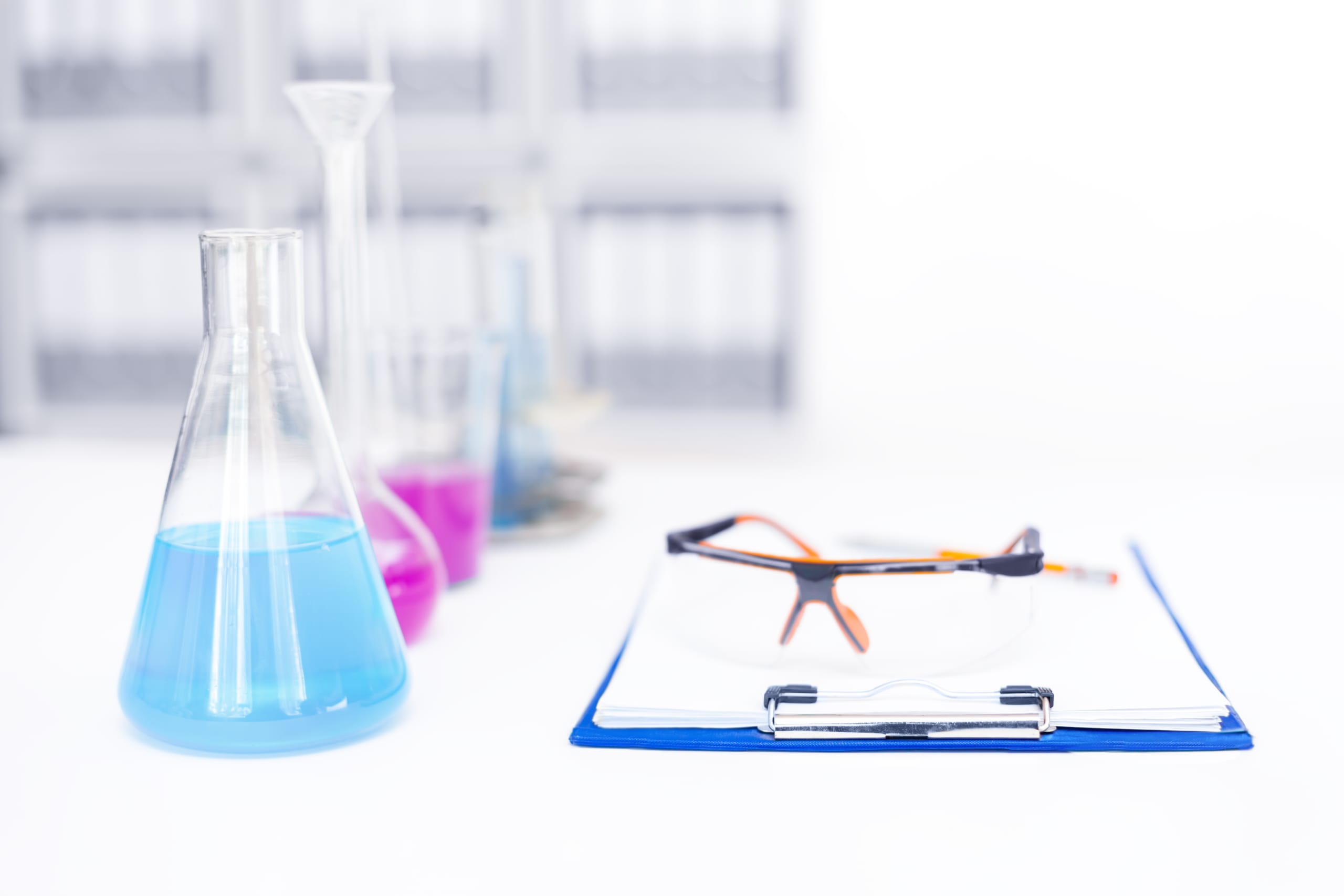 Chemicals in beakers next to a certificate of analysis on a clipboard