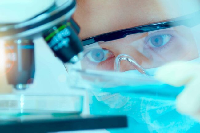 Close up of masked chemical technician analysing microscope||A table showing the quality parameters of water for different ISO grades||Two female scientists or technicians with face protective masks work in laboratory on human blood samples