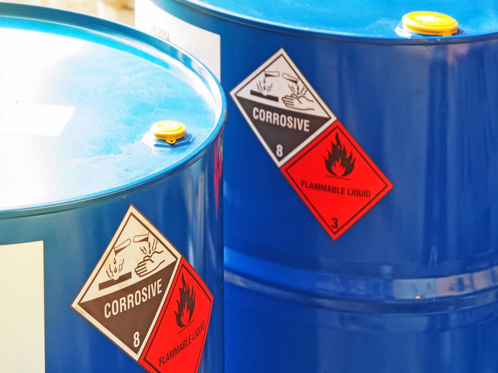 Blue chemical drum with corrosive and flammable hazard labels