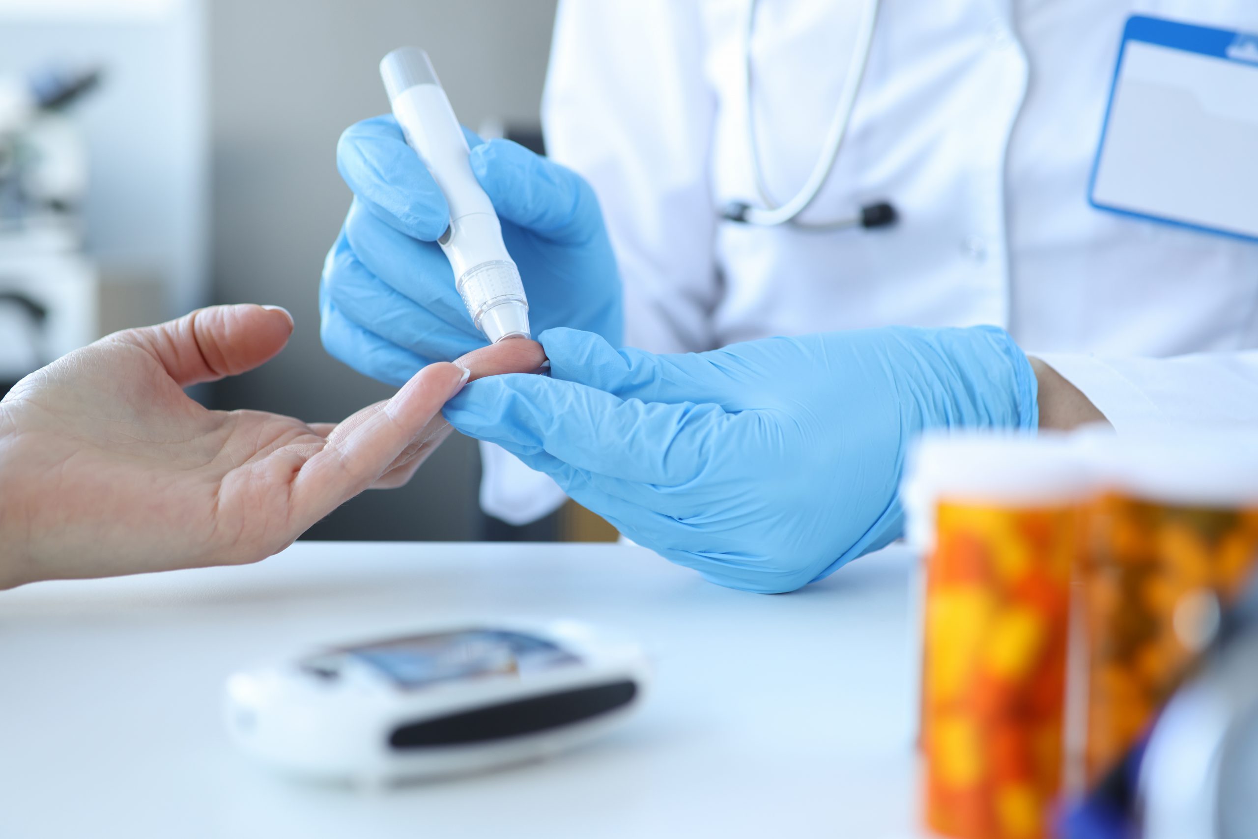 A doctor piercing a patient's finger with a lancet.