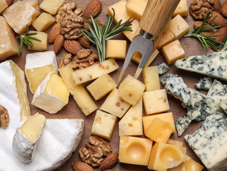 Cheese plate with rosemary and nuts on wooden board
