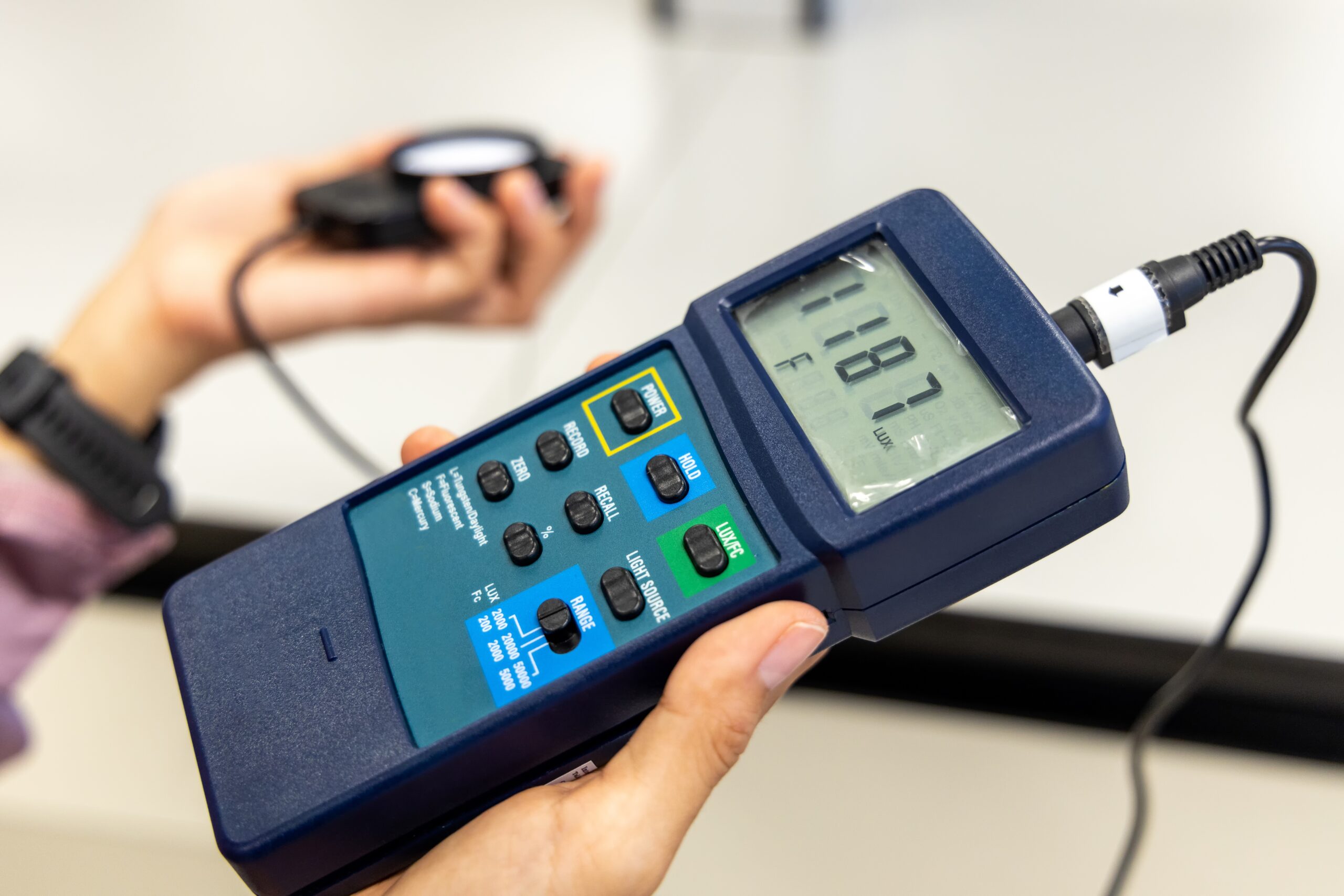 Person holding a digital light lux meter to read the intensity of light