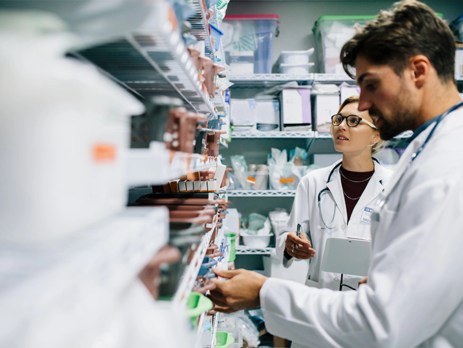 Two pharmacists working in a pharmacy||Two pharmacists in a lab with a microscope and samples of drugs