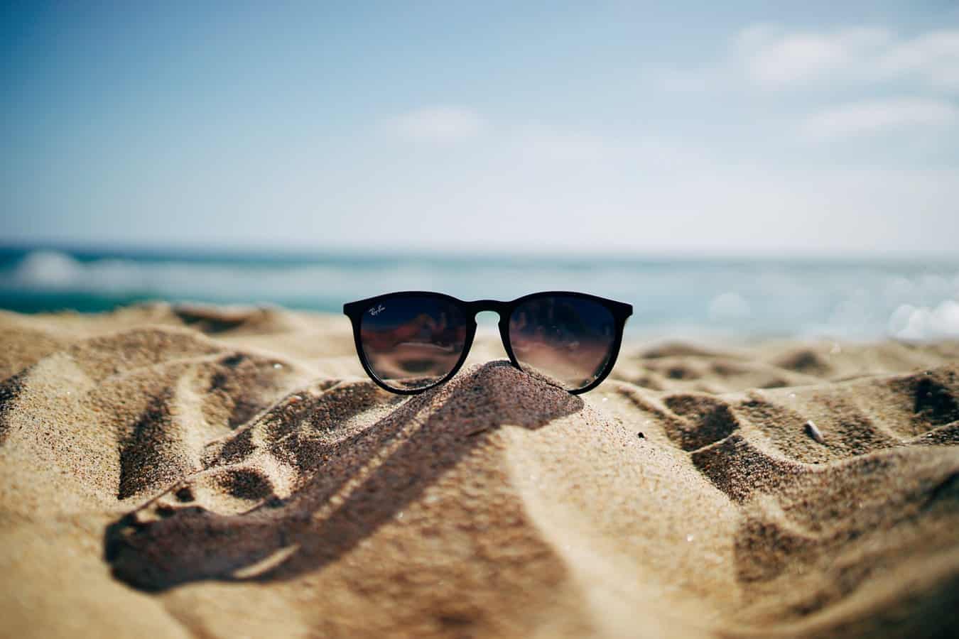 A pair of sunglasses on a mound of sand